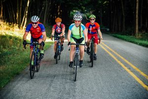 Pedal bicycles medium shot of four cyclists riding towards camera and smiling