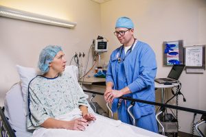 kalamazoo Anesthesiology surgeon talking to patient laying on bed