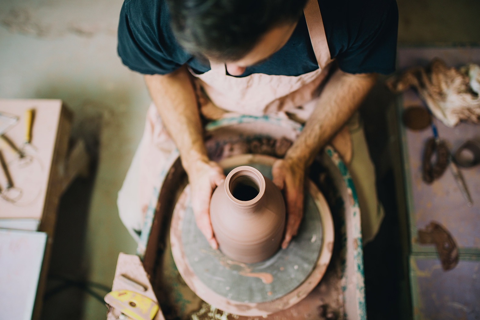 Garyling Ceramic Medium top down shot of man spinning a pottery vase while wearing a apron