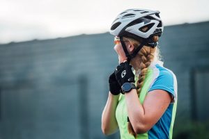 Pedal Bicycle female cyclist buckling helmet looking away from camera and smiling